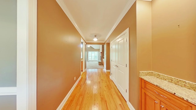 corridor with light wood-type flooring and ornamental molding