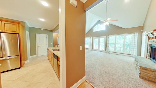 kitchen with ceiling fan, a brick fireplace, sink, light colored carpet, and stainless steel appliances