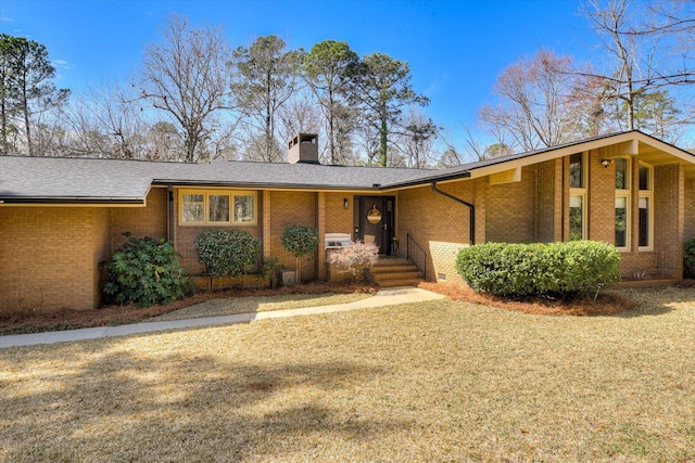 mid-century inspired home with a front yard, a shingled roof, a chimney, crawl space, and brick siding