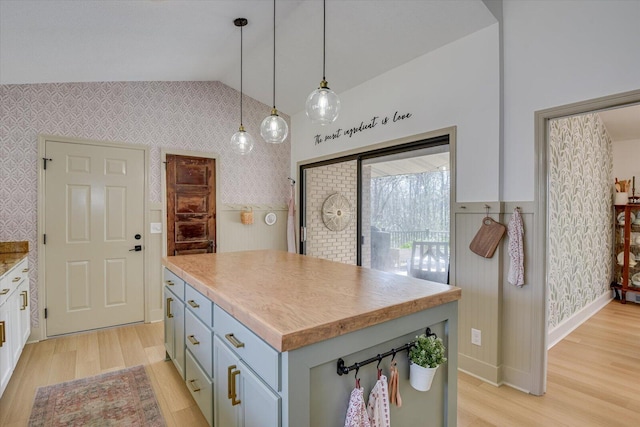 kitchen with a kitchen island, wallpapered walls, vaulted ceiling, light wood-style flooring, and hanging light fixtures