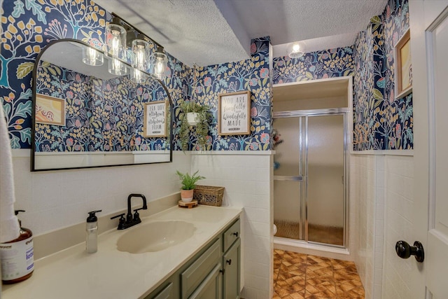 full bathroom featuring a wainscoted wall, a textured ceiling, tile walls, and wallpapered walls