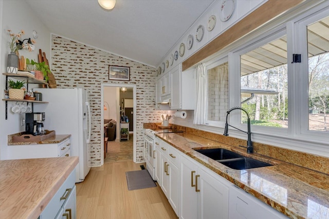 kitchen with white appliances, open shelves, a sink, vaulted ceiling, and white cabinetry