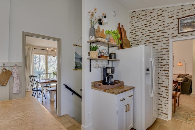 kitchen with white cabinetry, light wood-style floors, and white fridge with ice dispenser