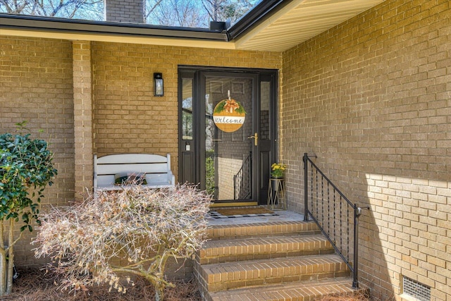 doorway to property featuring brick siding and a chimney