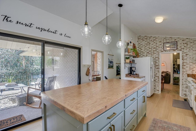 kitchen featuring decorative light fixtures, light countertops, light wood-type flooring, vaulted ceiling, and freestanding refrigerator