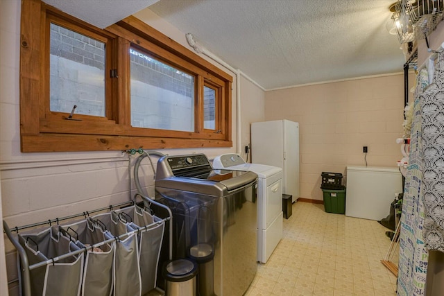 clothes washing area featuring a textured ceiling, separate washer and dryer, concrete block wall, light floors, and laundry area