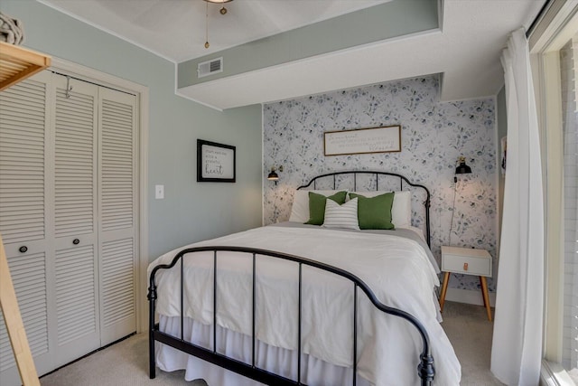 bedroom featuring visible vents, light colored carpet, a closet, and wallpapered walls