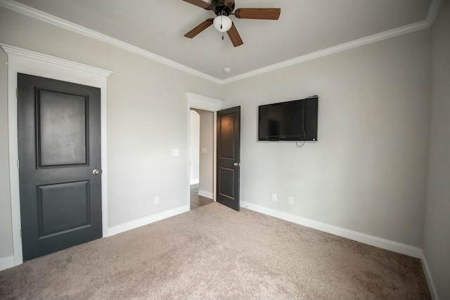 unfurnished bedroom featuring carpet, crown molding, and baseboards