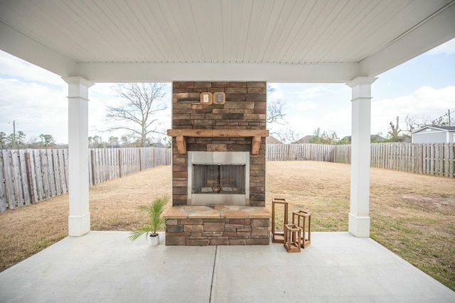 view of patio featuring an outdoor stone fireplace and a fenced backyard