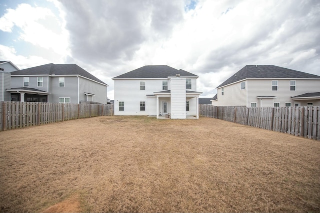 rear view of property with a fenced backyard and a yard