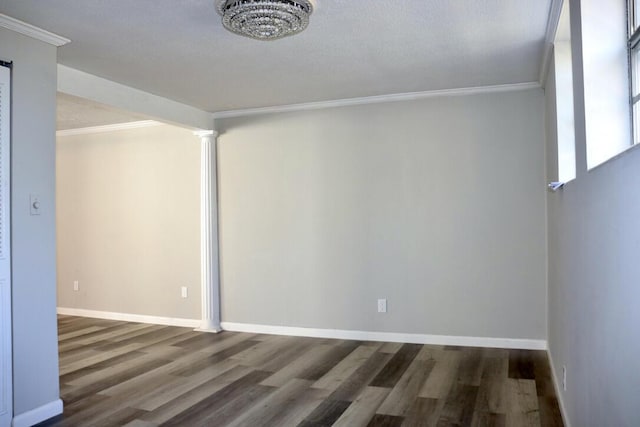 empty room with baseboards, wood finished floors, ornamental molding, and decorative columns