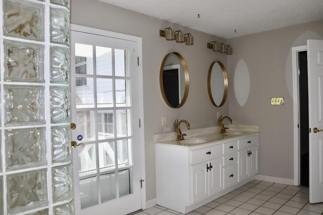 full bath featuring tile patterned flooring, double vanity, baseboards, and a sink