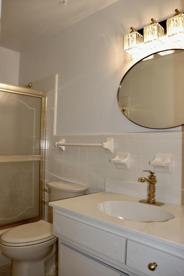 bathroom with vanity, tile walls, toilet, and a shower with shower door