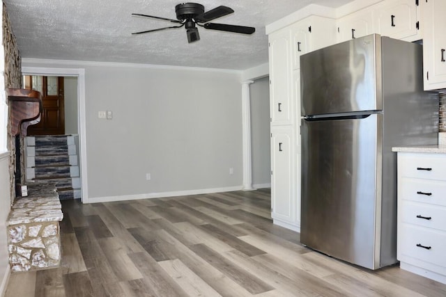 kitchen featuring light wood-style flooring, a textured ceiling, freestanding refrigerator, and ceiling fan