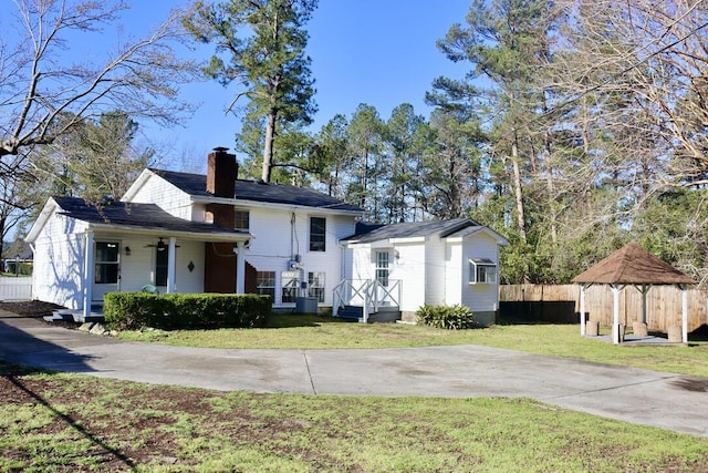 view of front of house with a gazebo, a front lawn, fence, and a chimney