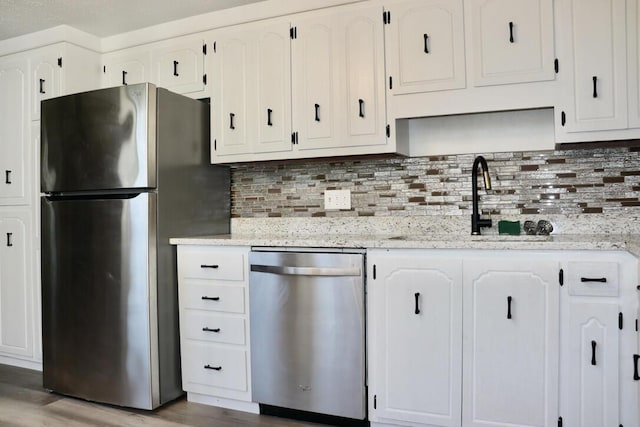 kitchen featuring decorative backsplash, light wood finished floors, appliances with stainless steel finishes, and white cabinetry