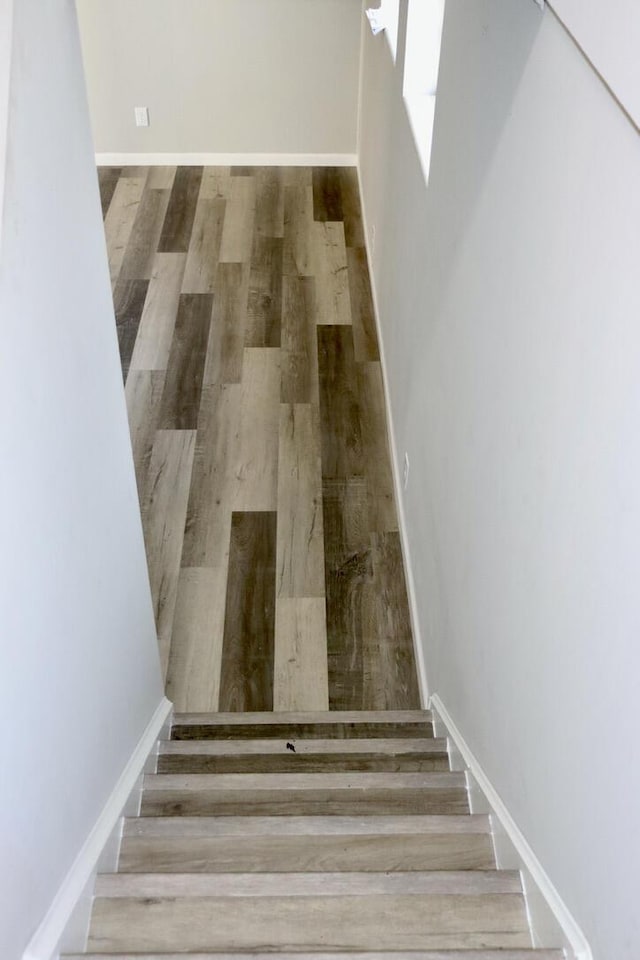 staircase featuring baseboards and wood finished floors