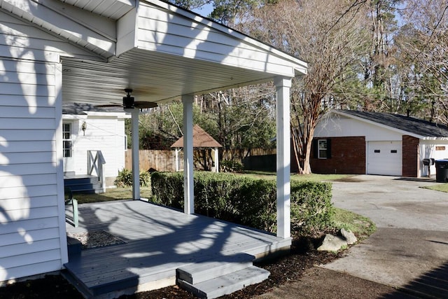 wooden deck with a garage, an outbuilding, ceiling fan, and fence