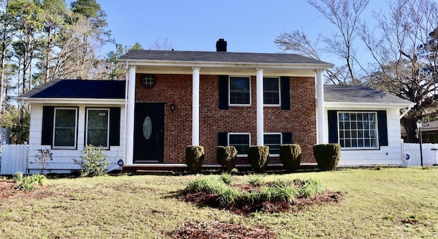 view of front facade featuring a front lawn, fence, and brick siding