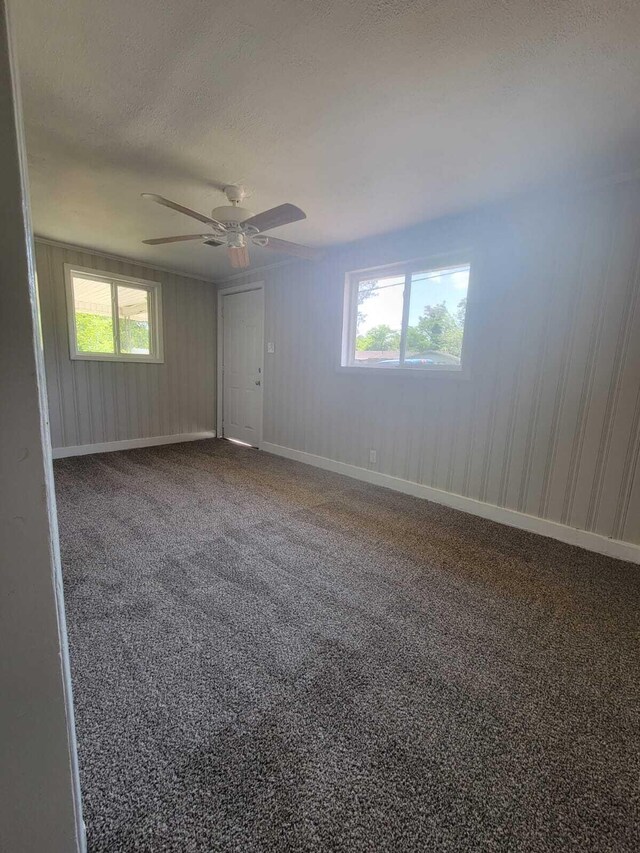 empty room featuring ceiling fan, carpet, and a textured ceiling