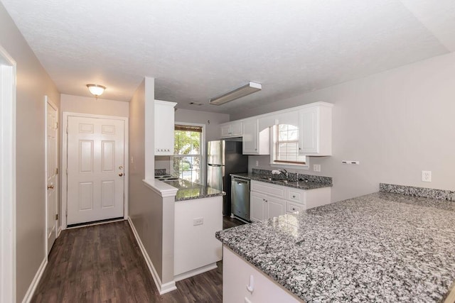 kitchen with stone counters, dishwasher, dark hardwood / wood-style floors, kitchen peninsula, and white cabinets