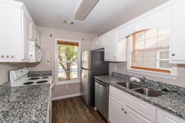 kitchen featuring dark wood-type flooring, dark stone counters, white cabinets, sink, and stainless steel appliances