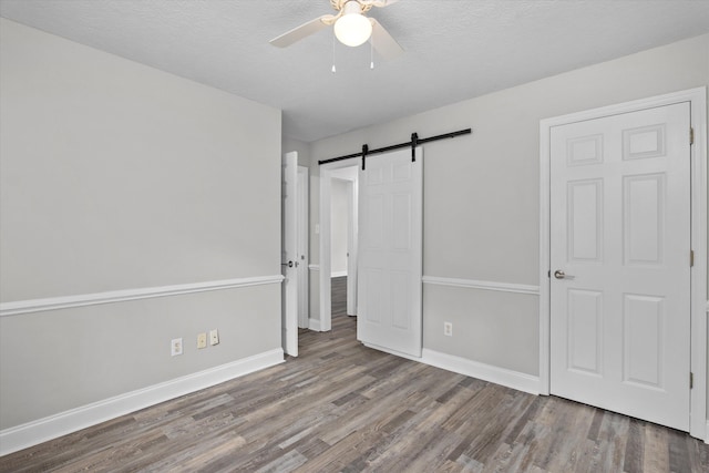 55 Charlestowne Dr, Augusta, GA 30907 - unfurnished bedroom featuring wood finished floors, a barn door, ceiling fan, and a textured ceiling