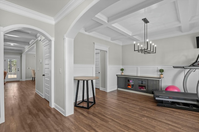 interior space with arched walkways, a wainscoted wall, coffered ceiling, and wood finished floors