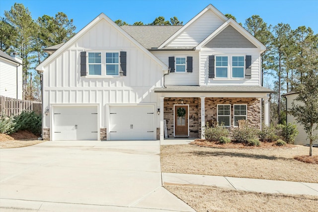 view of front of home with driveway, a shingled roof, stone siding, an attached garage, and board and batten siding