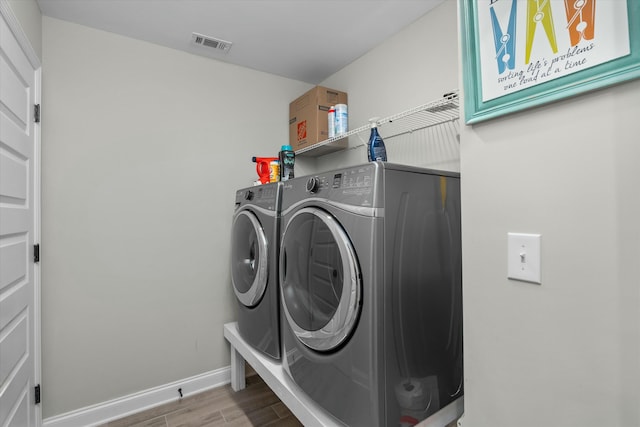 laundry room with laundry area, wood finished floors, visible vents, baseboards, and washer and clothes dryer