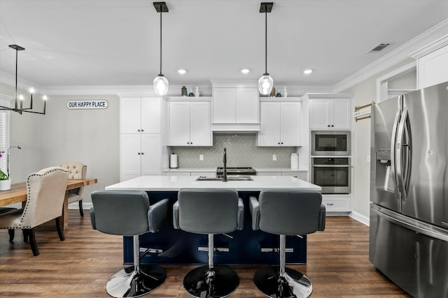 kitchen with appliances with stainless steel finishes, a kitchen island with sink, light countertops, crown molding, and a sink