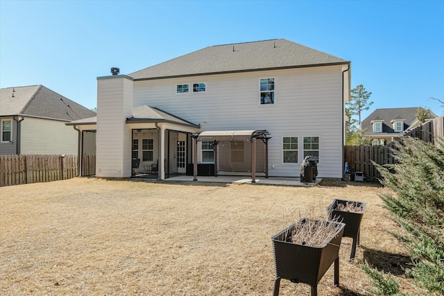 rear view of house with a fenced backyard, a chimney, a shingled roof, and a patio