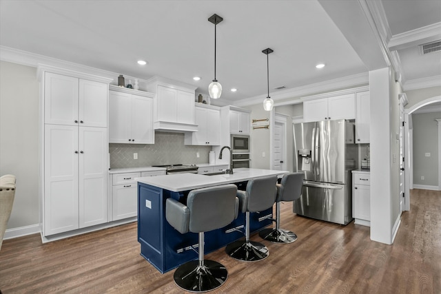 kitchen featuring arched walkways, crown molding, light countertops, appliances with stainless steel finishes, and white cabinets