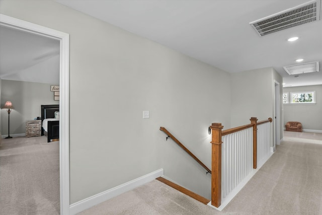 hall featuring light colored carpet, visible vents, attic access, an upstairs landing, and baseboards