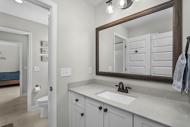 bathroom featuring toilet, ensuite bathroom, vanity, tile patterned flooring, and baseboards