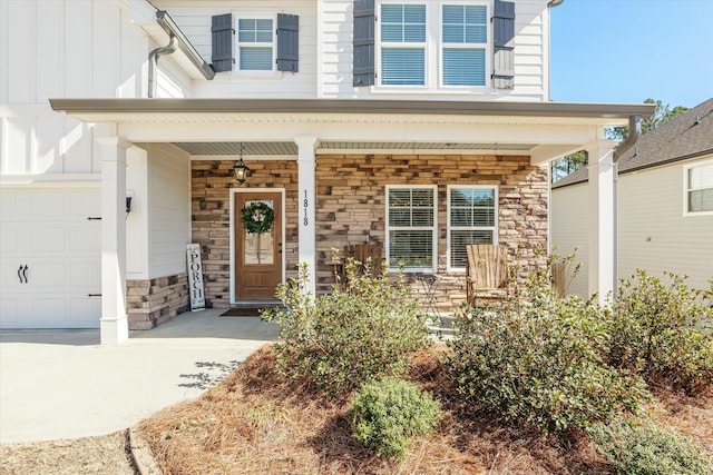 view of exterior entry featuring an attached garage, stone siding, covered porch, and board and batten siding