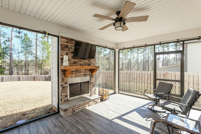 sunroom / solarium featuring ceiling fan and a fireplace