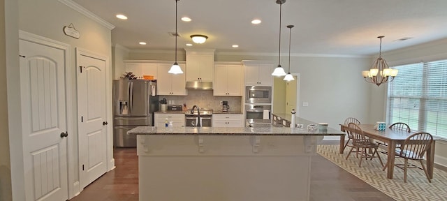 kitchen featuring white cabinetry, an island with sink, dark stone countertops, a kitchen bar, and stainless steel appliances