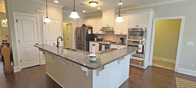 kitchen featuring sink, a breakfast bar area, white cabinetry, appliances with stainless steel finishes, and pendant lighting