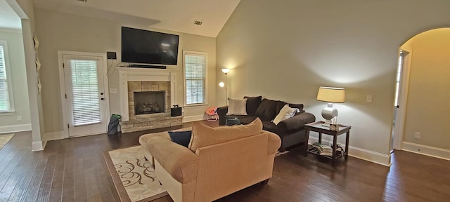 living room featuring a stone fireplace, high vaulted ceiling, and dark hardwood / wood-style flooring