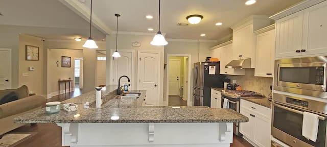 kitchen featuring pendant lighting, sink, appliances with stainless steel finishes, a kitchen bar, and decorative backsplash