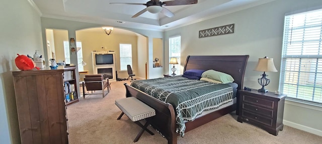 carpeted bedroom featuring a raised ceiling, crown molding, and ceiling fan