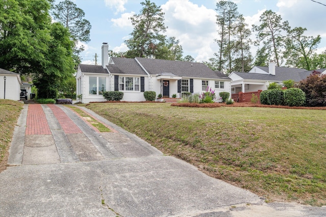 ranch-style home featuring a chimney, driveway, and a front lawn