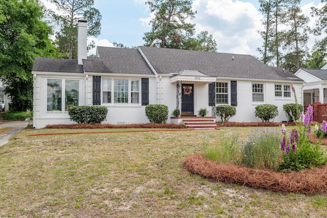 single story home with a chimney, a front lawn, and brick siding