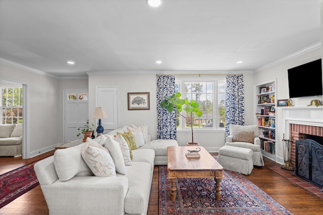 living room featuring dark wood-type flooring, crown molding, a brick fireplace, and recessed lighting