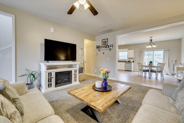 living room featuring ceiling fan with notable chandelier and light carpet