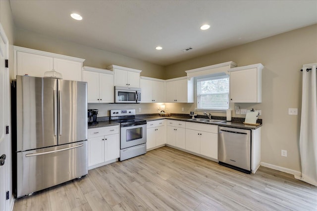 kitchen featuring stainless steel appliances, white cabinetry, sink, and light wood-type flooring