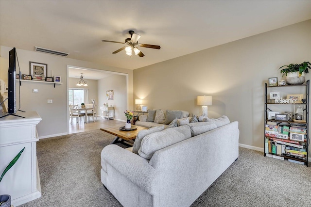 living room featuring carpet floors and ceiling fan with notable chandelier