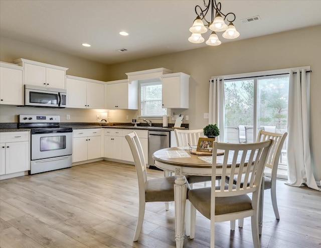 kitchen featuring a chandelier, stainless steel appliances, hanging light fixtures, plenty of natural light, and light hardwood / wood-style flooring