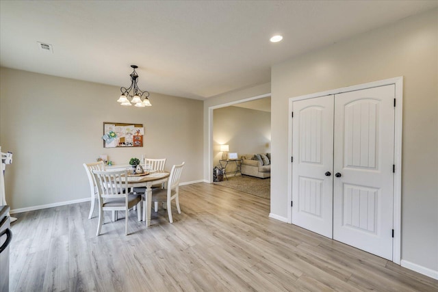 dining room featuring light wood-type flooring and a notable chandelier